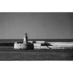Black-and-white lighthouse on a stone harbor breakwater