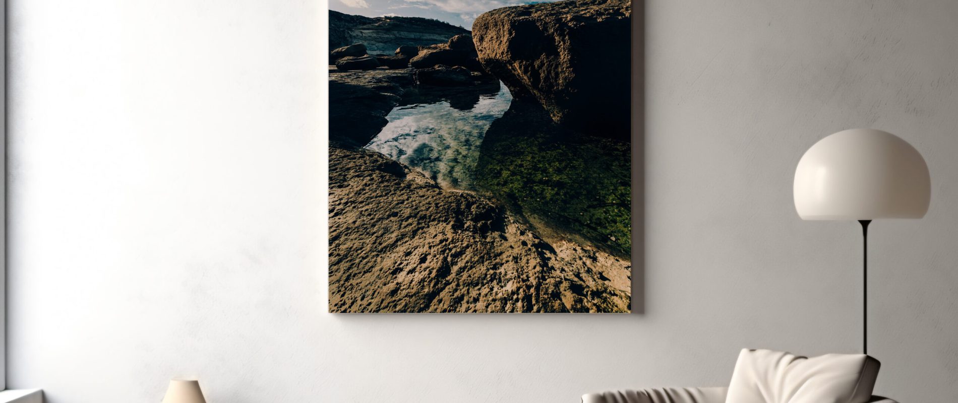 In a living room, a large canvas print of the Gozo Qbajjar Coastline adorns the wall above a chair, contributing to the room's inviting atmosphere