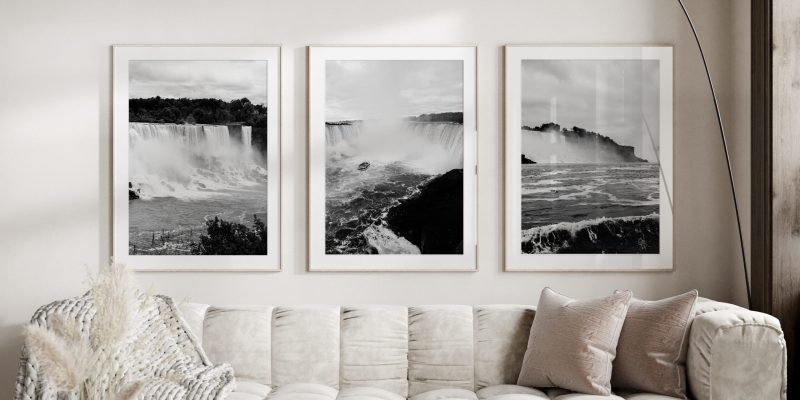 3 photo frames of Niagara falls in black and white hanged above a white sofa in a living room